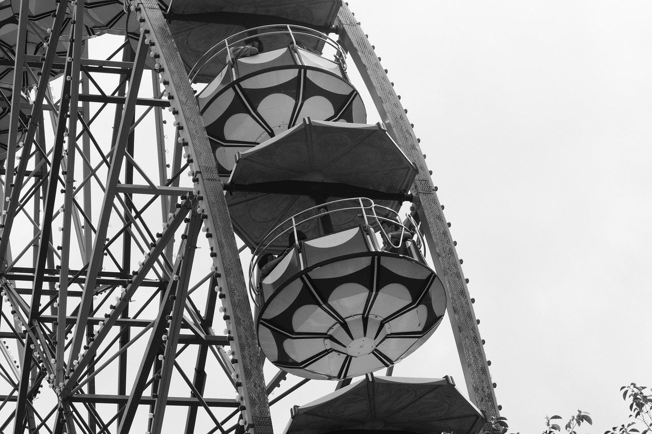 Low angle of a ferris wheel's steel frame and gondolas in black and white.